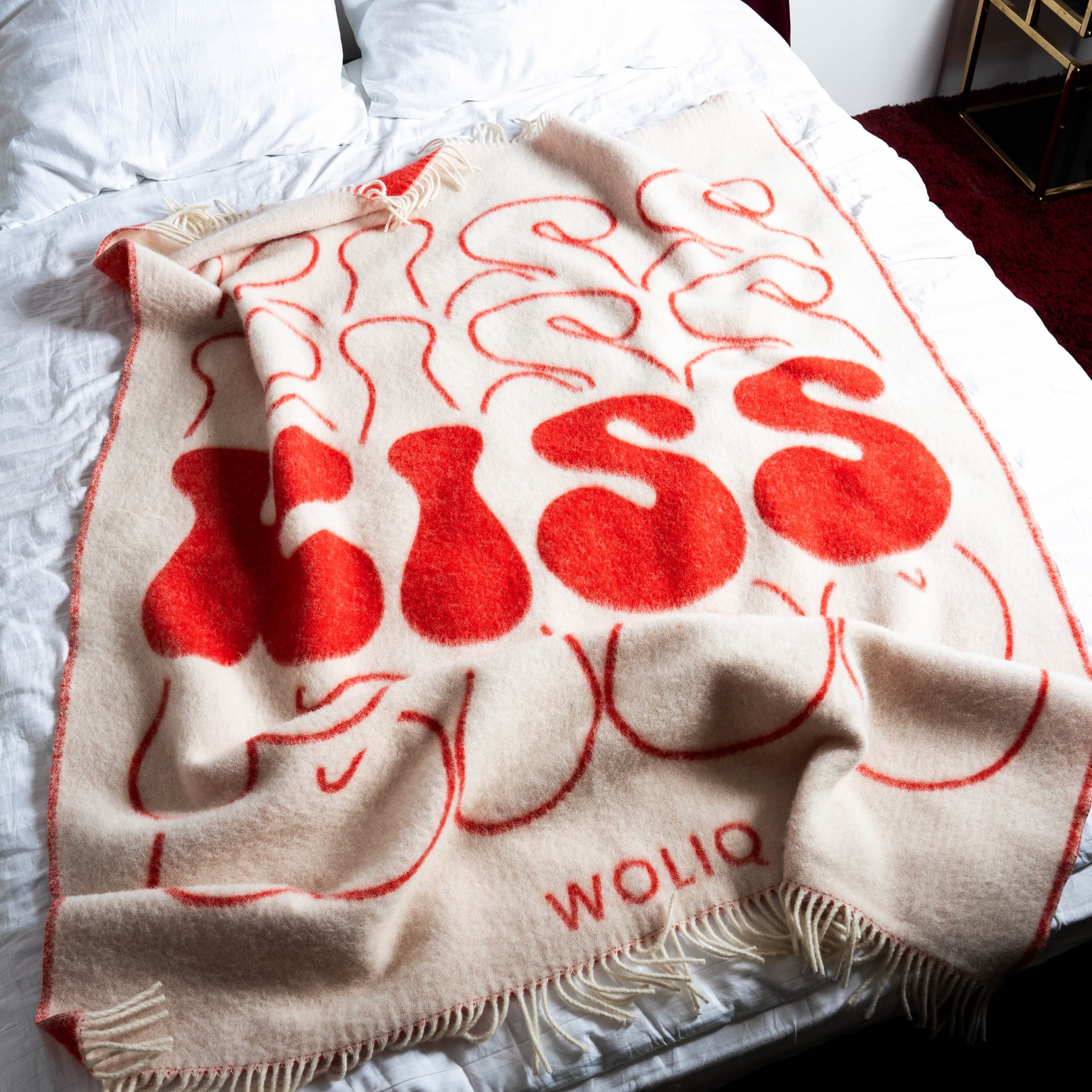 Red and white wool blanket draped on bed – WOLIQ Bold Kiss