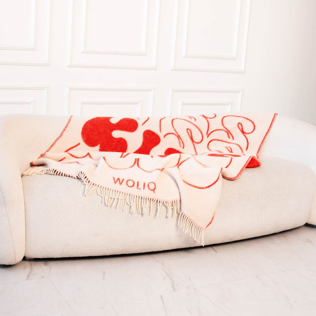 Red and white wool blanket styled on sofa – WOLIQ Bold Kiss