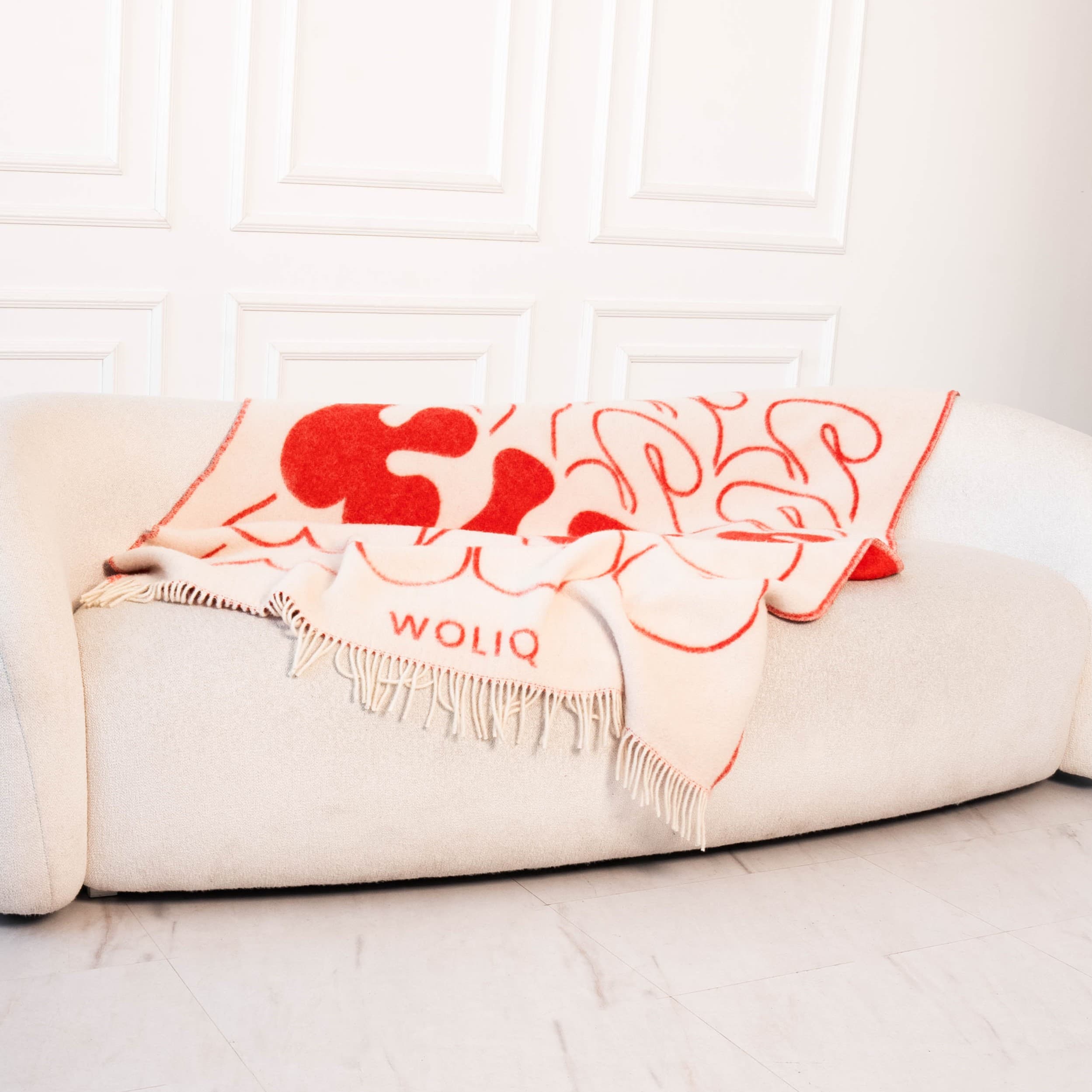 Red and white wool blanket styled on sofa – WOLIQ Bold Kiss