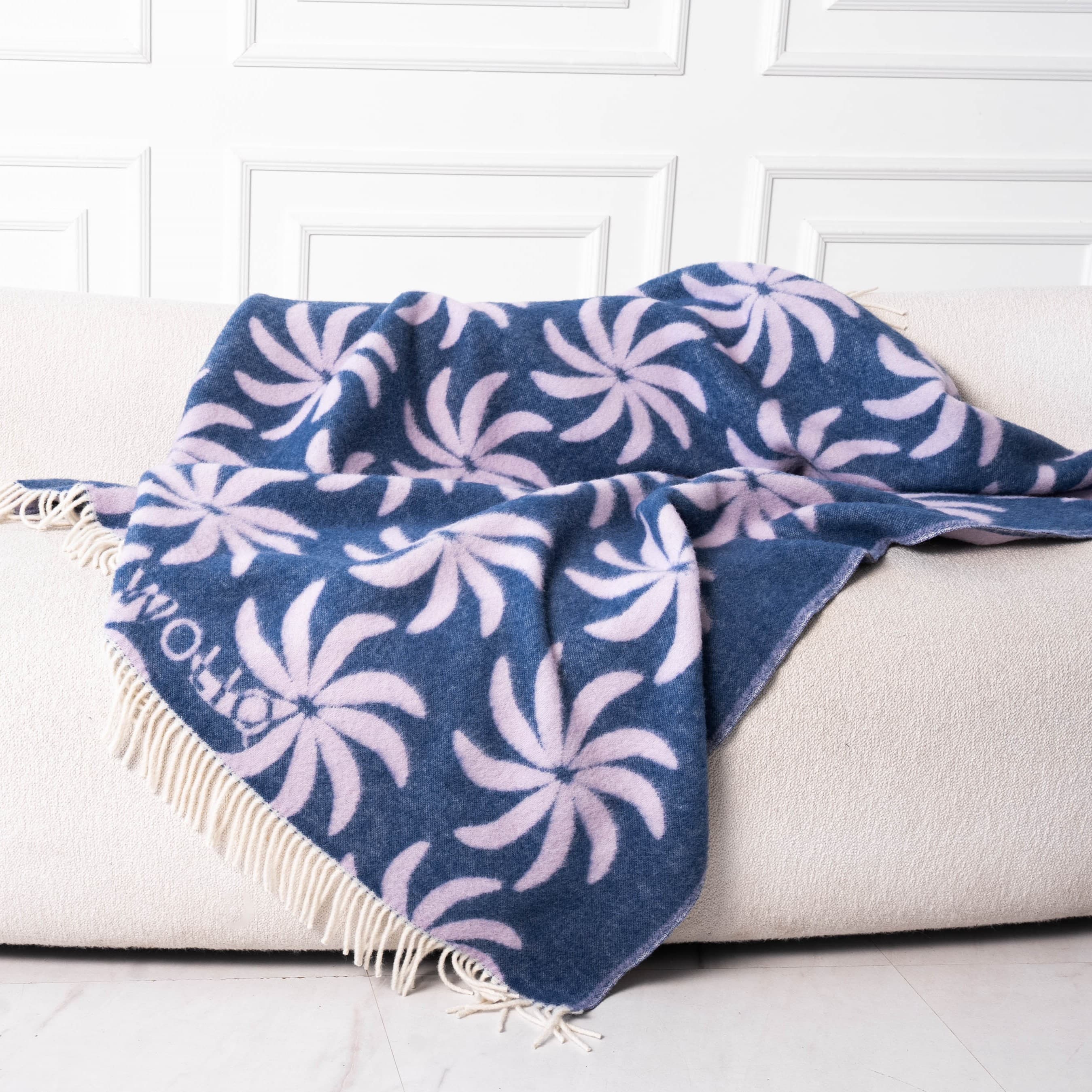 Blue and lilac floral wool blanket draped on sofa – WOLIQ Coastal Bloom
