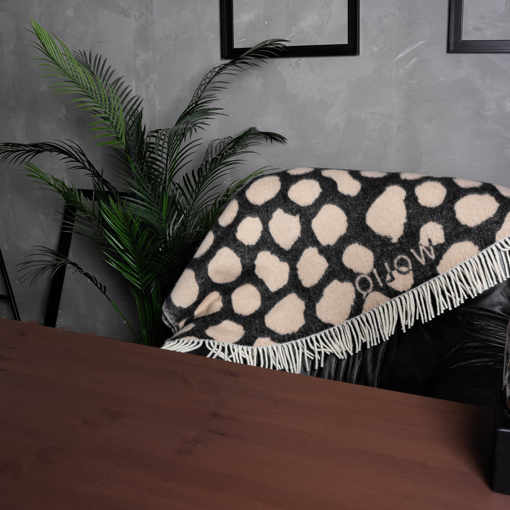 Black and brown cow print wool blanket draped over chair back – WOLIQ Earthbound