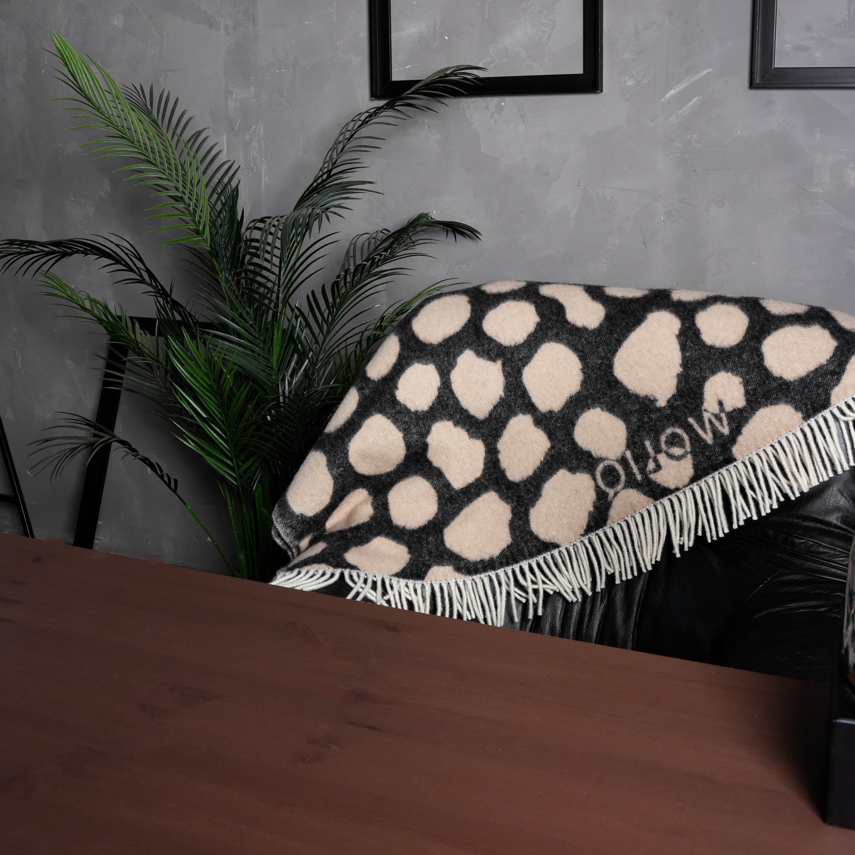 Black and brown cow print wool blanket draped over chair back – WOLIQ Earthbound