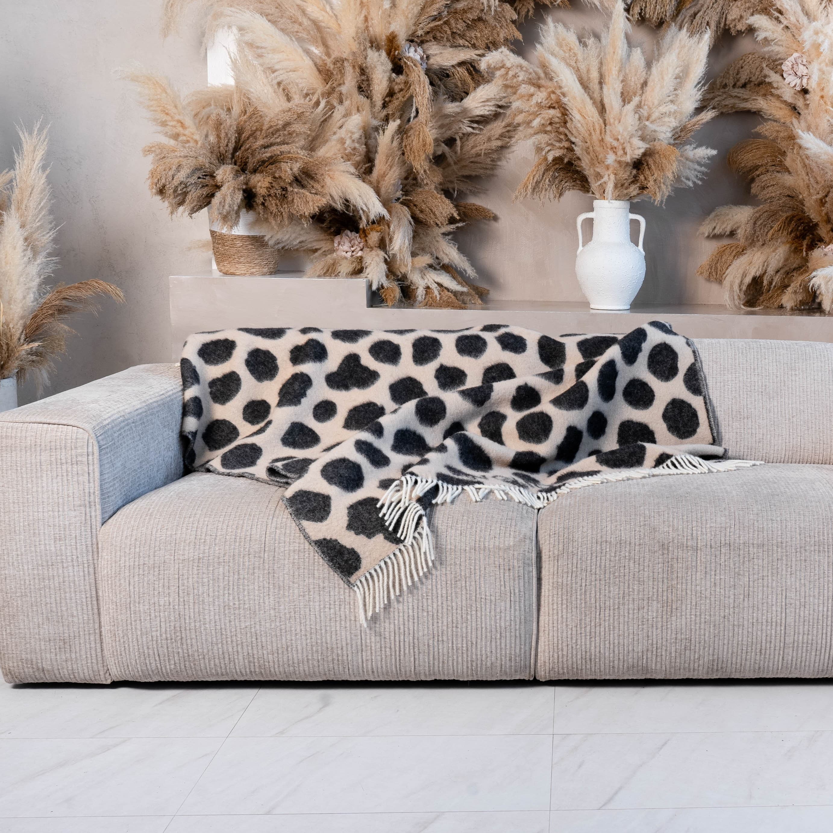 Black and brown cow print wool blanket draped on sofa – WOLIQ Earthbound
