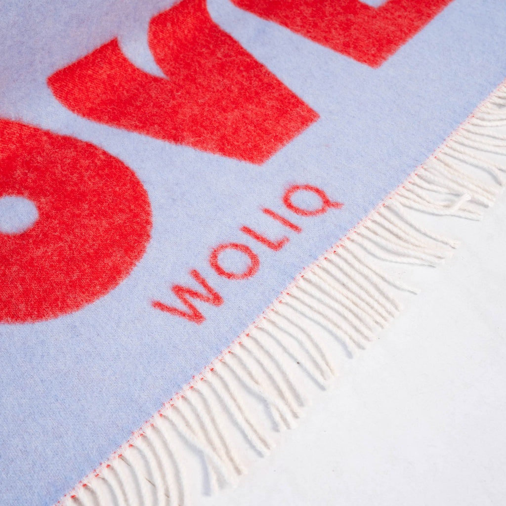 Close-up of logo on red and light blue wool blanket – WOLIQ Endless Love