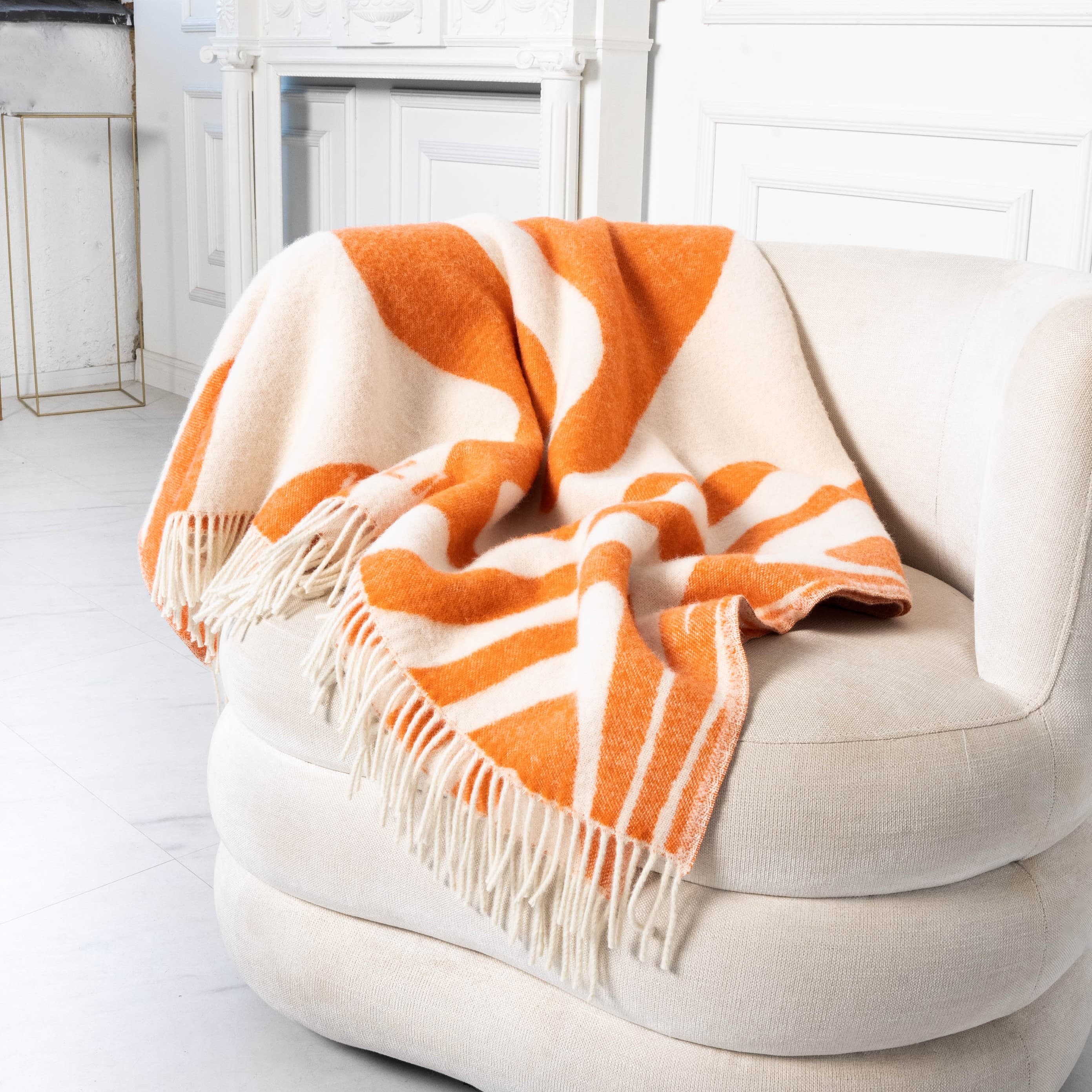 Orange and white flow pattern wool blanket draped on sofa – WOLIQ Flow Illusion