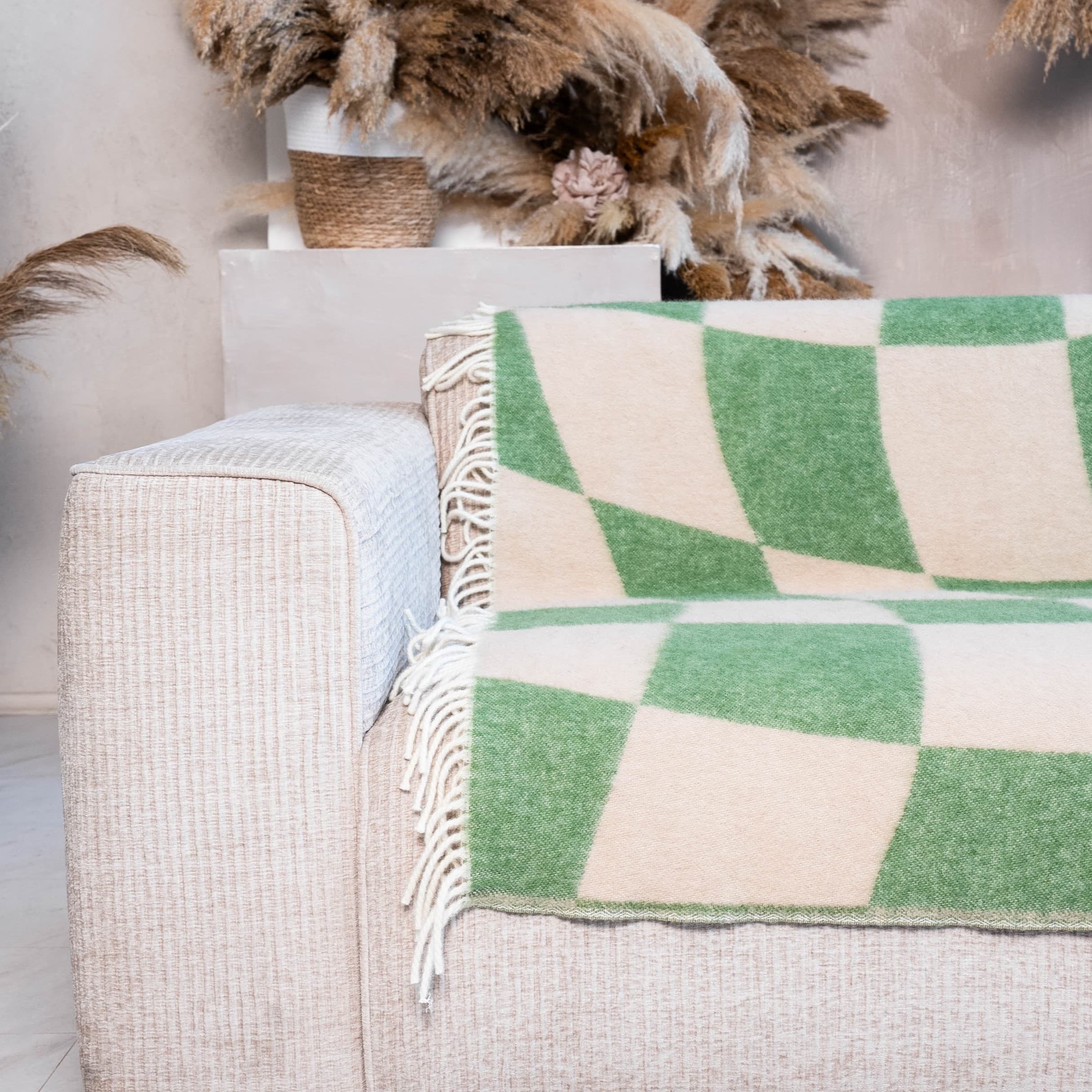 Close-up of green and beige cube illusion wool blanket on sofa – WOLIQ Gentle Shift