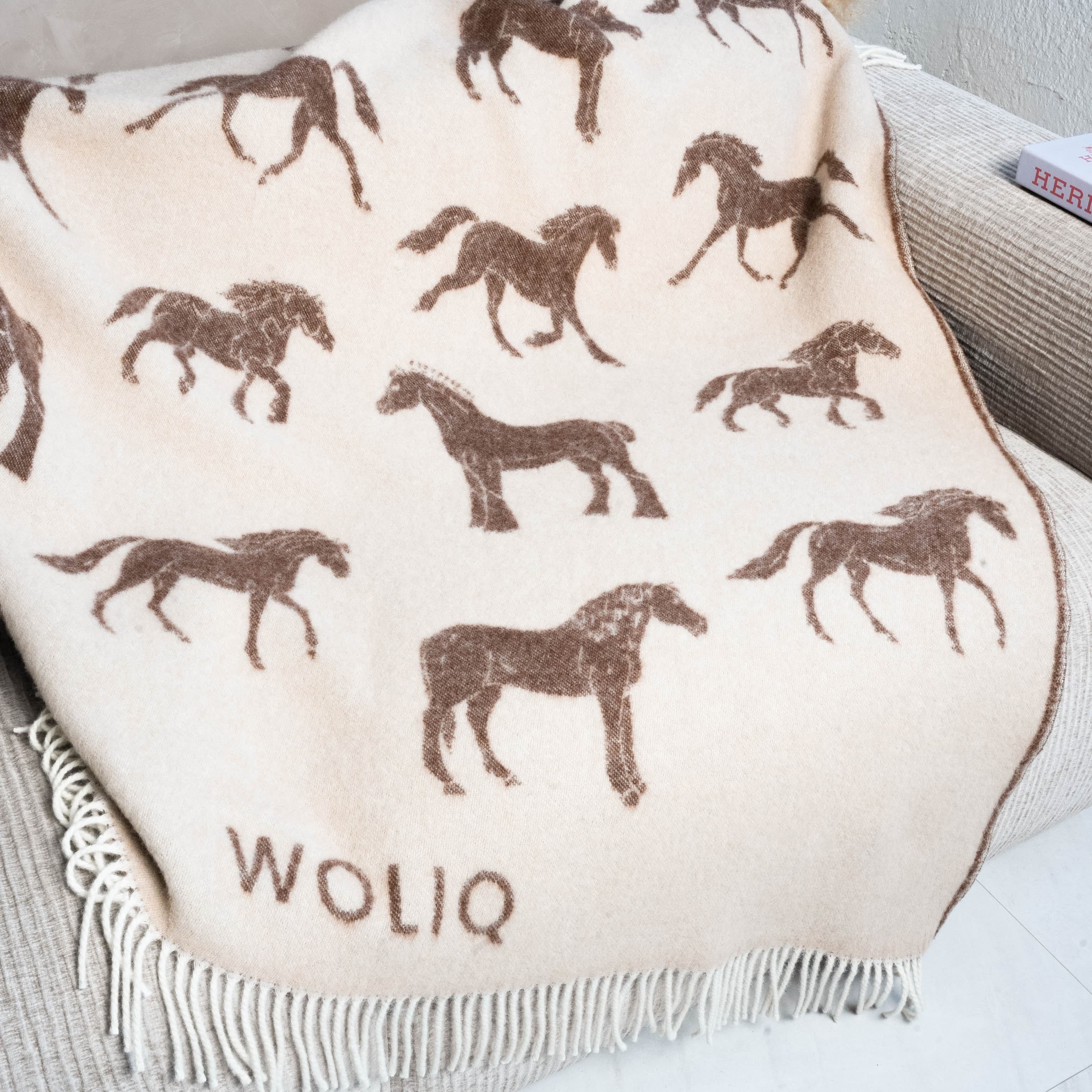 Close-up of brown horse pattern wool blanket on sofa – WOLIQ Gentle Wild