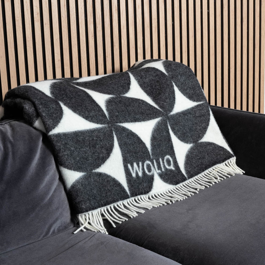Black and white Bauhaus wool blanket neatly placed on sofa – WOLIQ Mono Bauhaus