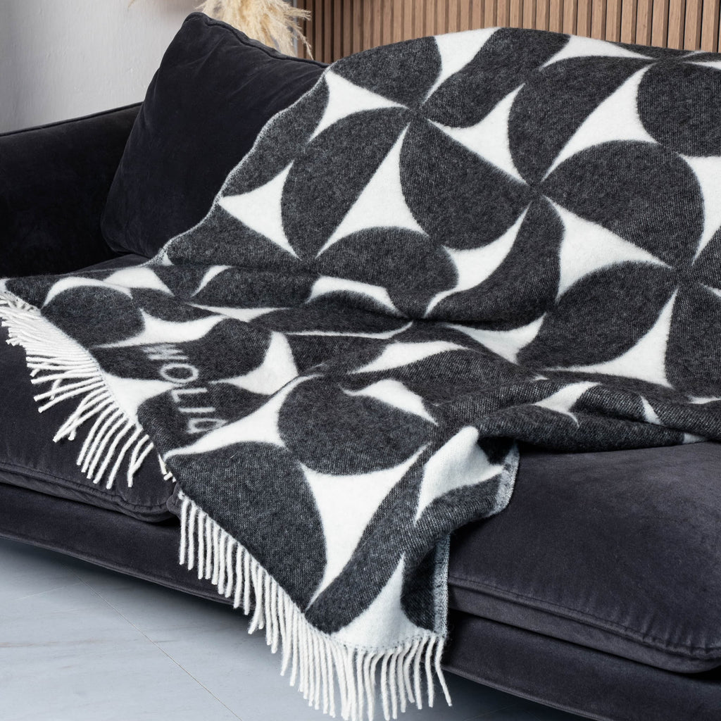 Black and white Bauhaus wool blanket draped on sofa – WOLIQ Mono Bauhaus