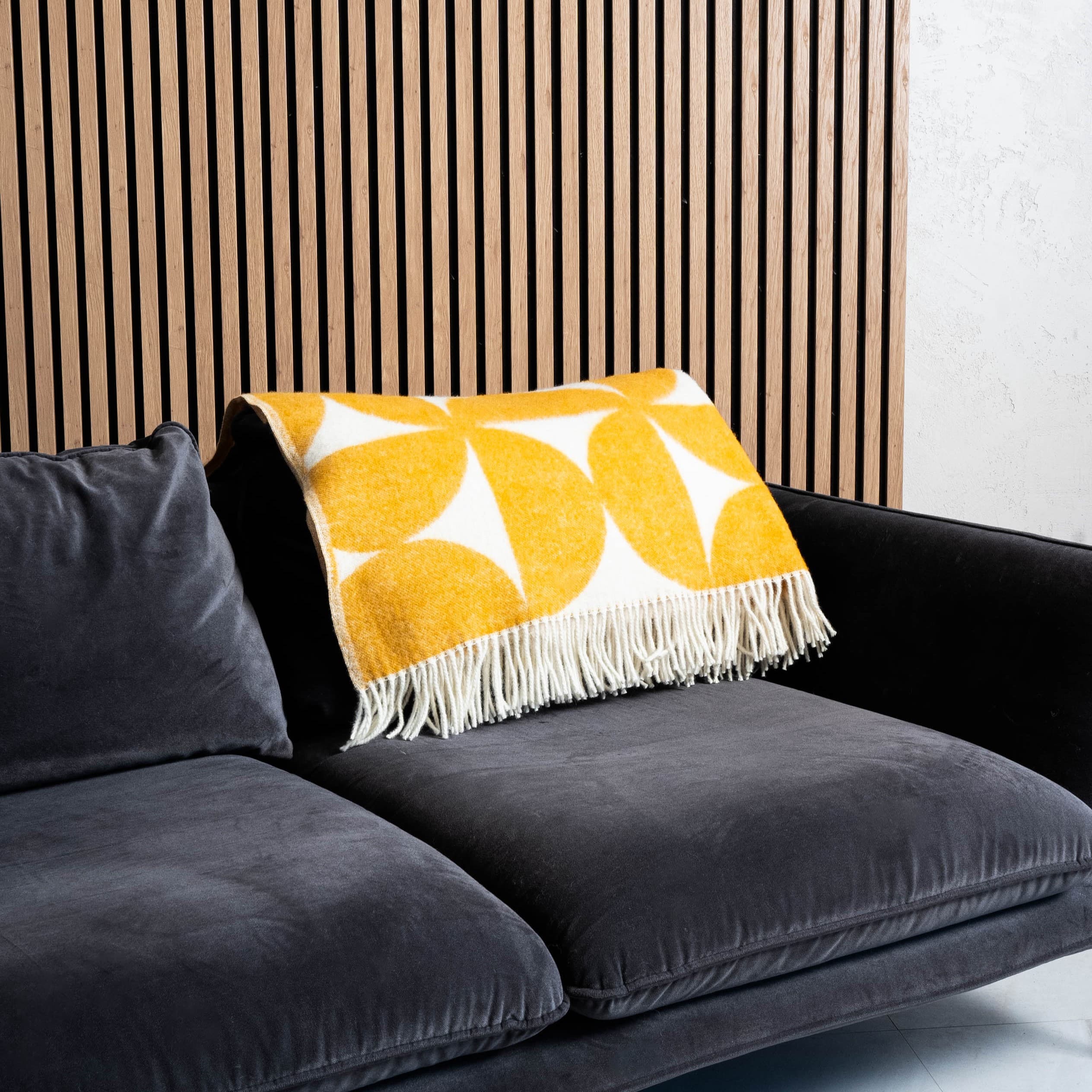 Yellow and white Bauhaus wool blanket neatly placed on sofa back – WOLIQ Solar Bauhaus