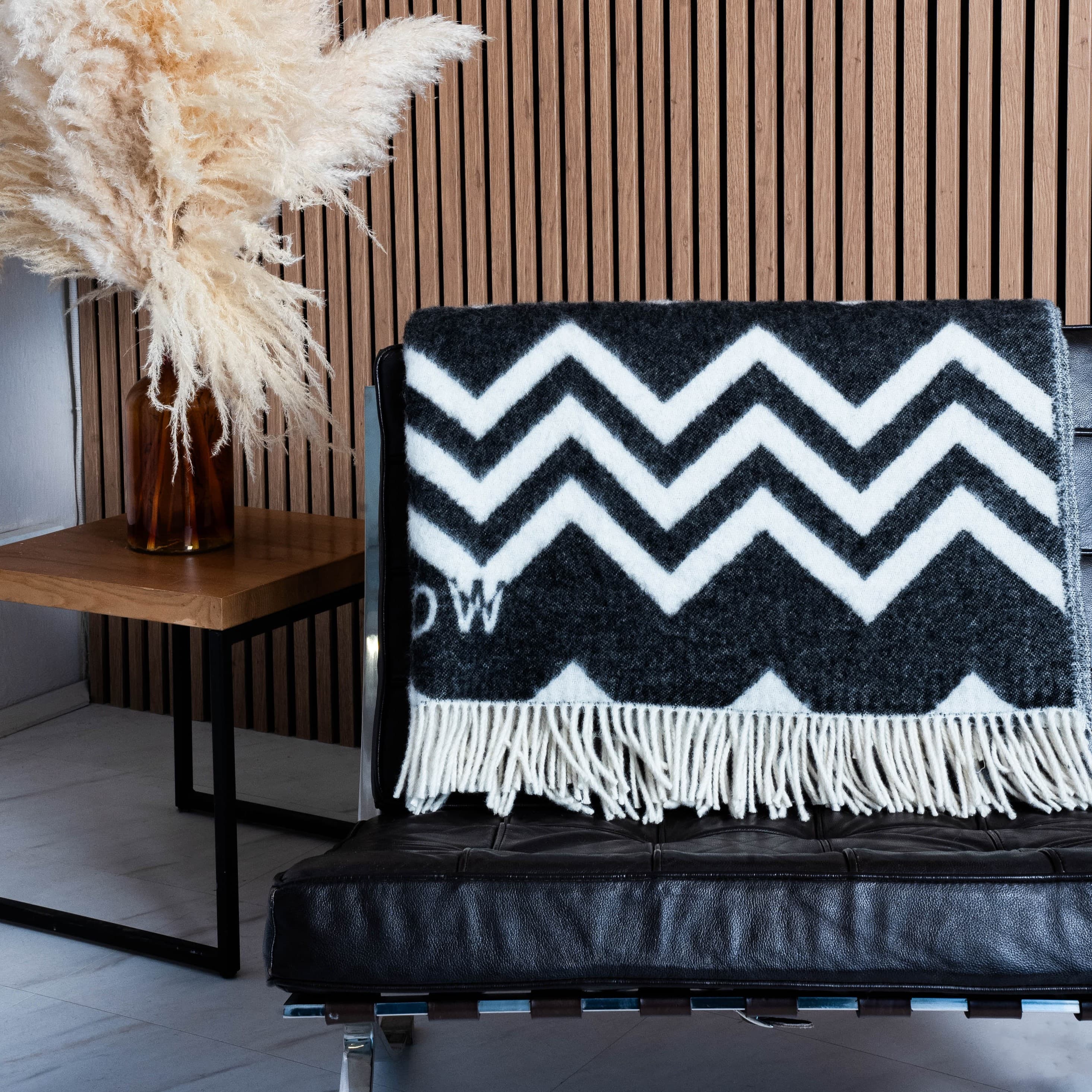 Black and white zigzag wool blanket draped over chair back – WOLIQ Static Motion