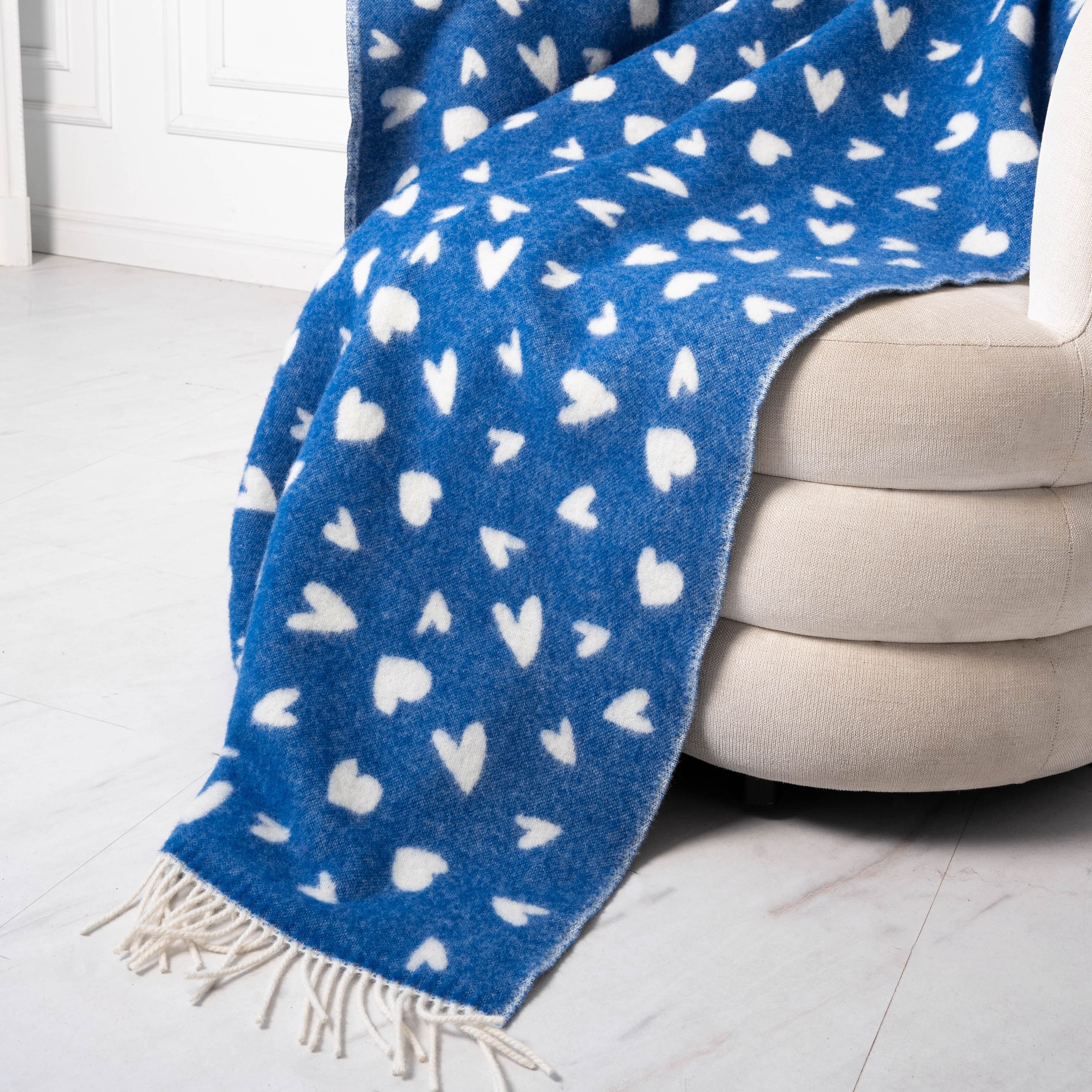 Close-up of white and blue heart pattern wool blanket on sofa – WOLIQ Tender Drift