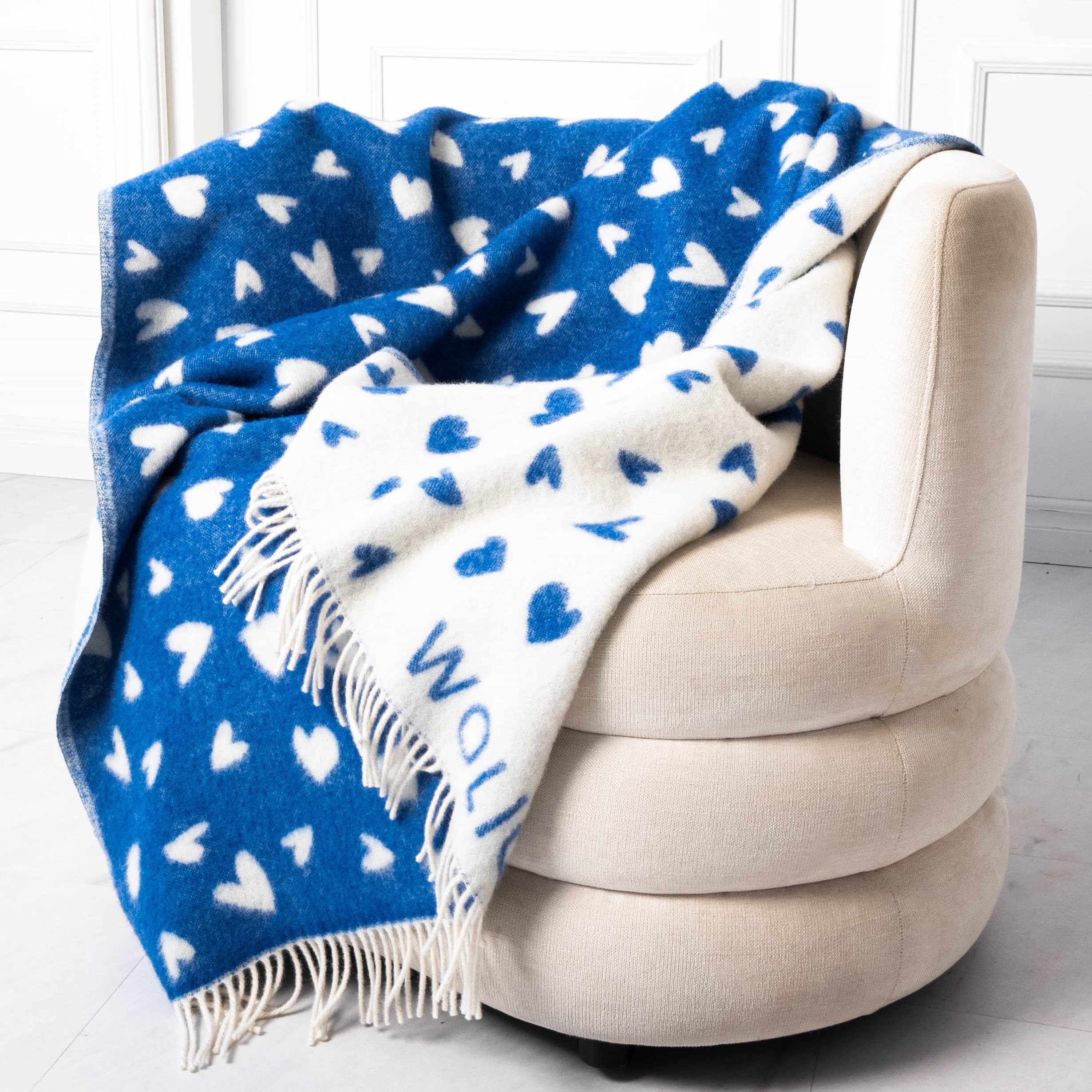 White and blue heart pattern wool blanket on sofa – WOLIQ Tender Drift