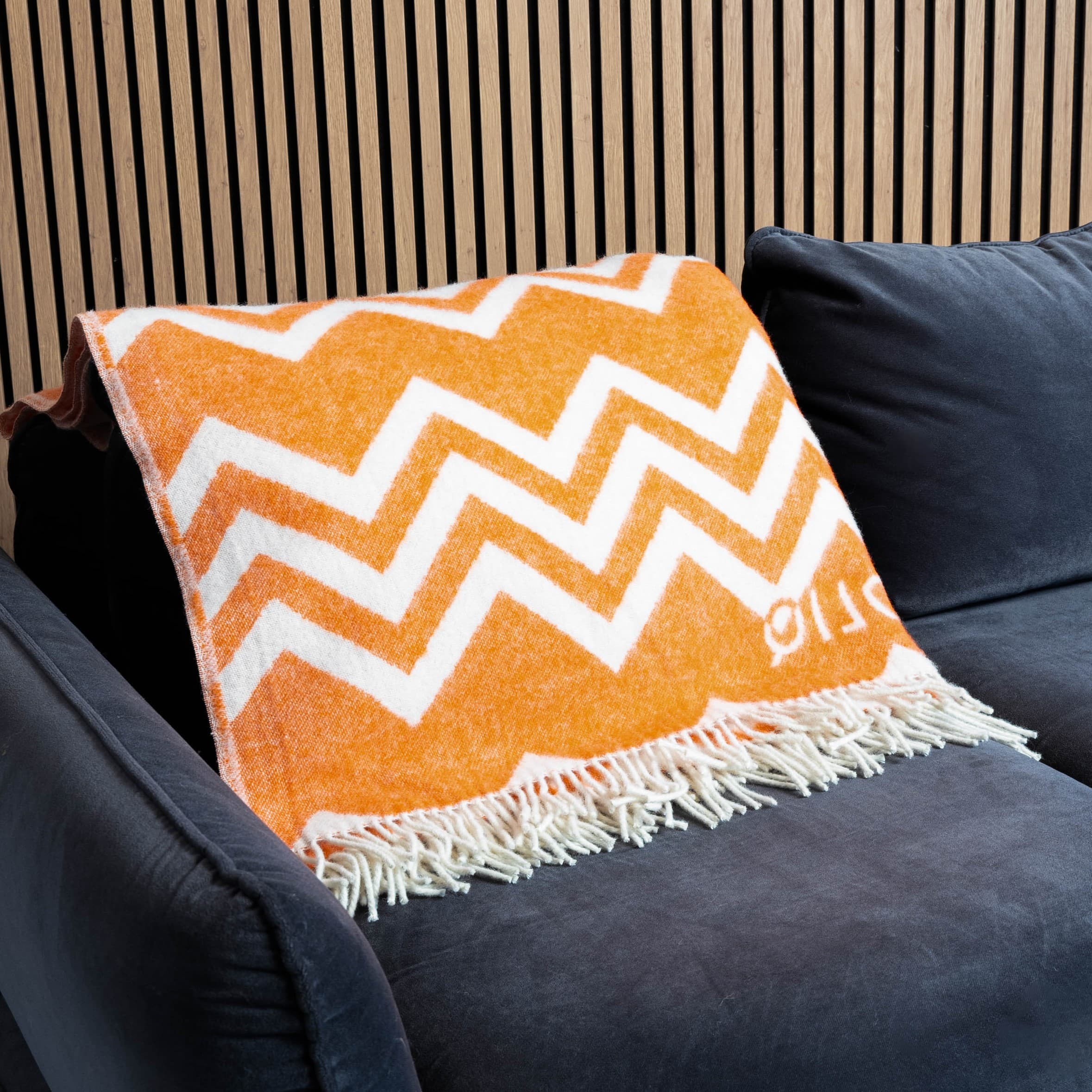 Orange and white zigzag wool blanket on sofa – WOLIQ Warm Glow