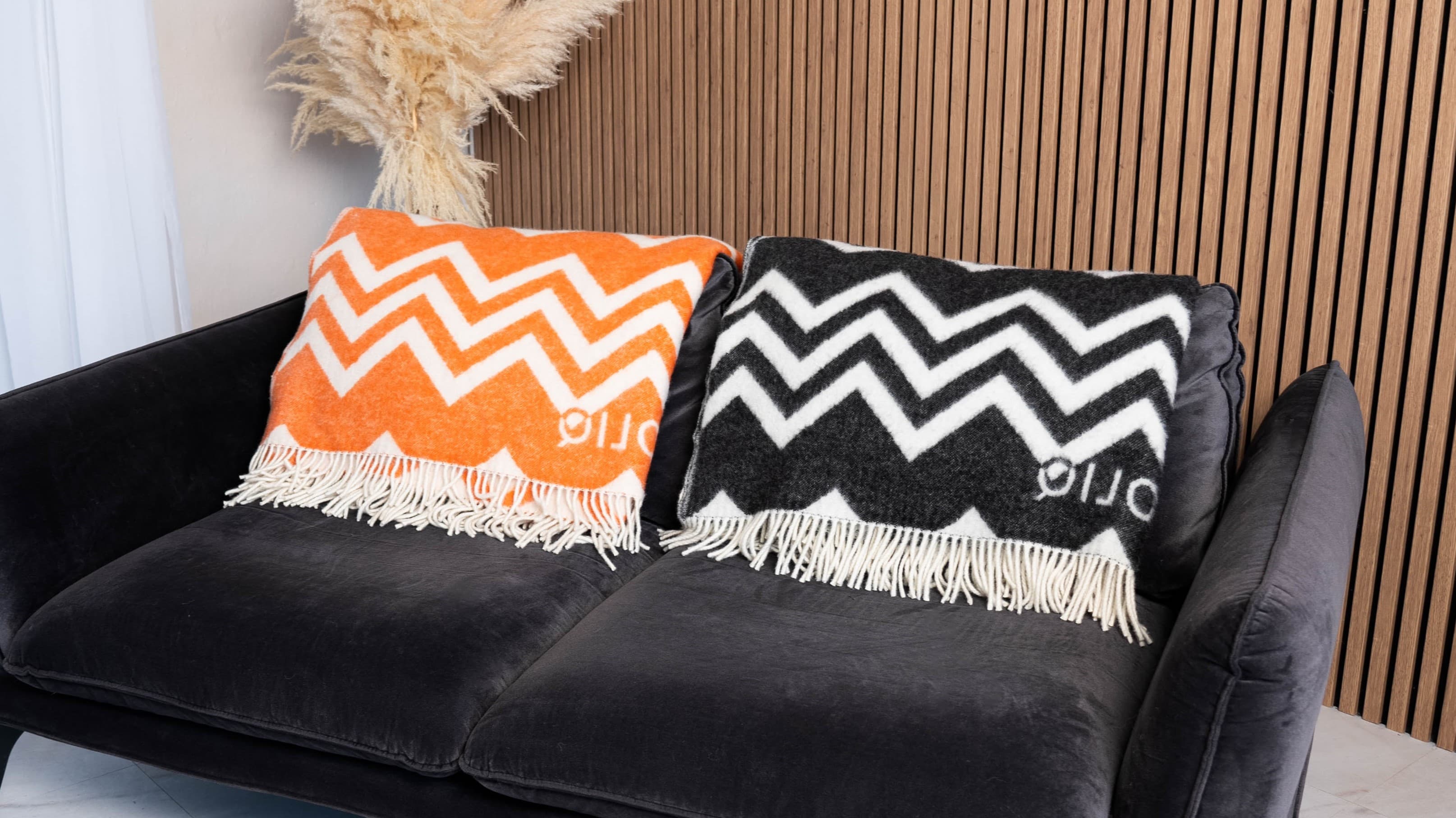 Two wool blankets on sofa in a modern interior - WOLIQ.